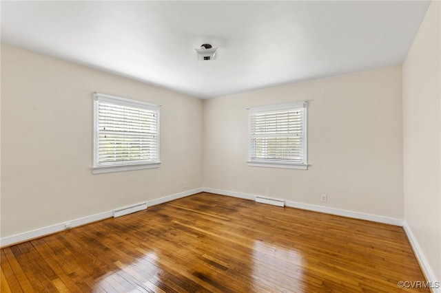 spare room featuring baseboards, visible vents, and wood-type flooring