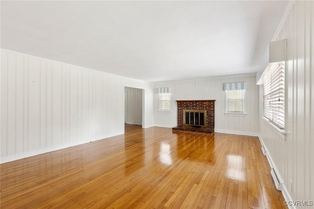 unfurnished living room featuring a brick fireplace and light wood-type flooring
