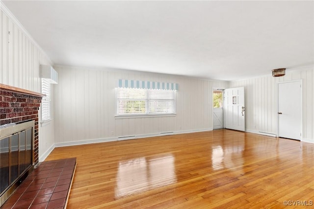 unfurnished living room with a fireplace, light wood-type flooring, visible vents, baseboards, and a baseboard radiator