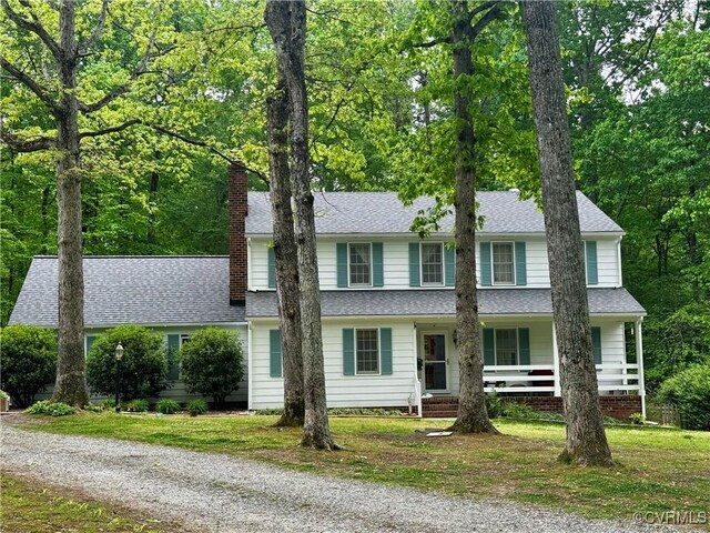 view of front of property featuring a porch, a chimney, roof with shingles, and gravel driveway