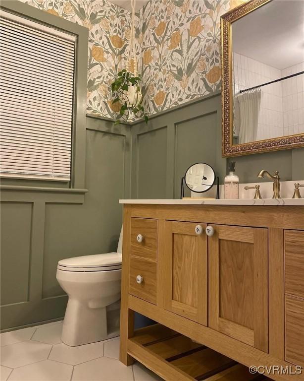 bathroom with a decorative wall, a wainscoted wall, toilet, and wallpapered walls
