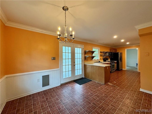 kitchen featuring a notable chandelier, brick patterned floor, french doors, stainless steel appliances, and a peninsula