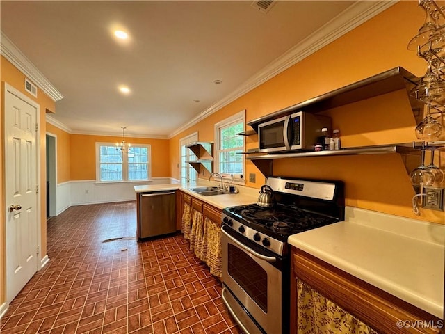 kitchen with light countertops, a wainscoted wall, brick patterned floor, ornamental molding, and stainless steel appliances