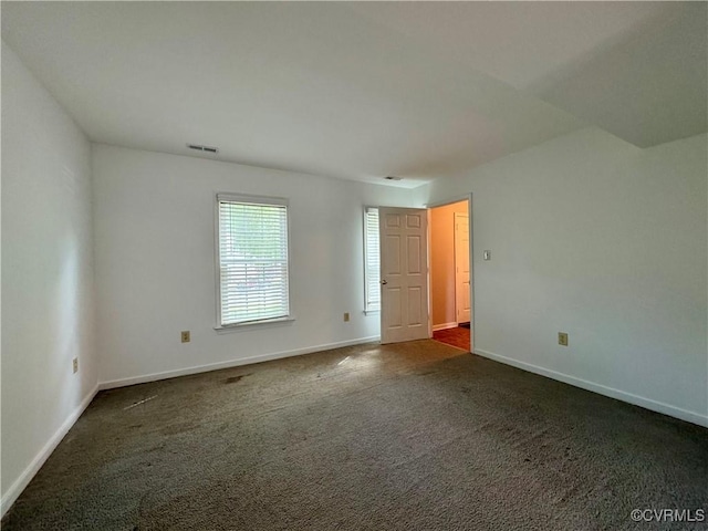 empty room featuring baseboards, visible vents, and dark carpet