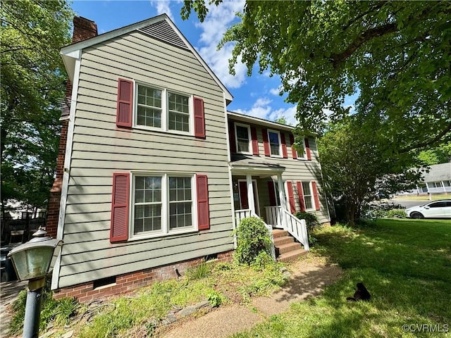 view of front of home with a chimney, a front yard, and crawl space