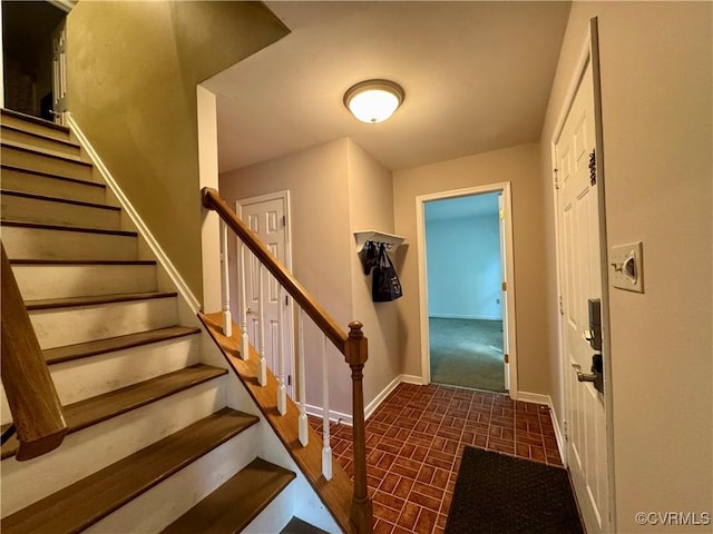 stairs featuring baseboards and brick patterned floor