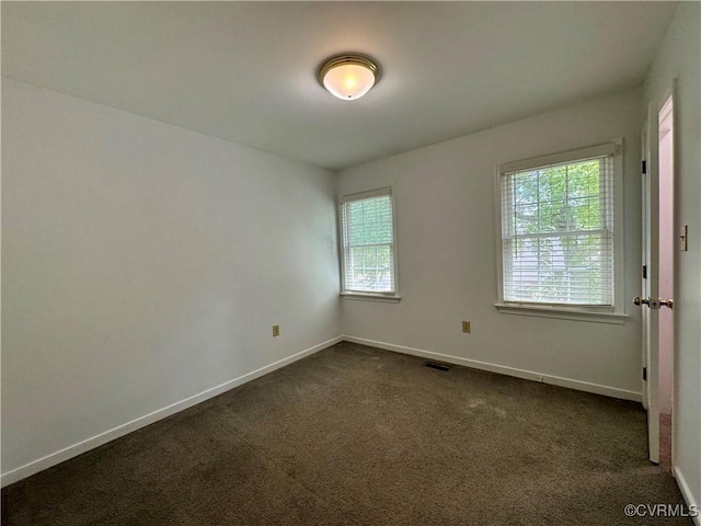 empty room featuring visible vents, baseboards, and dark colored carpet