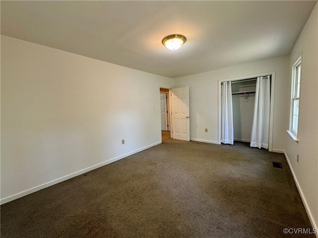 unfurnished bedroom with visible vents, baseboards, dark carpet, and a closet