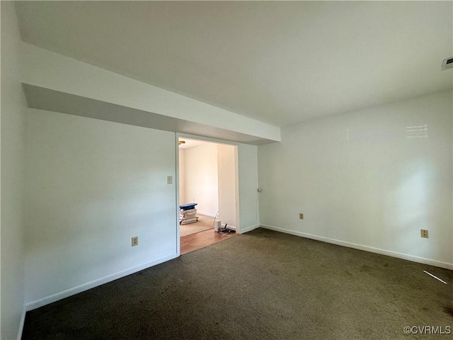spare room featuring dark carpet, baseboards, and visible vents