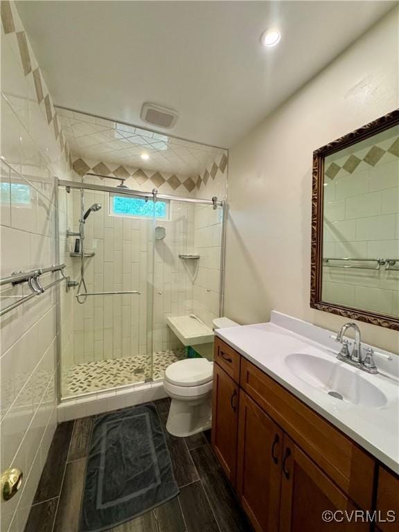 bathroom with vanity, toilet, wood finish floors, and a stall shower