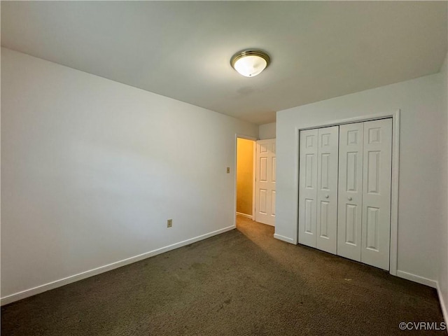 unfurnished bedroom featuring a closet, baseboards, and dark colored carpet