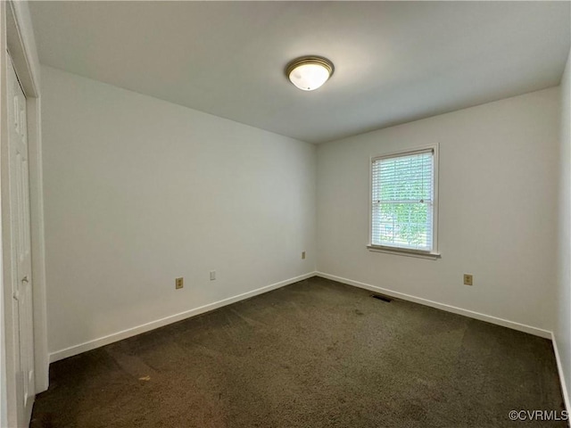 empty room featuring visible vents, baseboards, and dark colored carpet