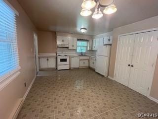 kitchen featuring baseboards, light countertops, white cabinets, and white appliances