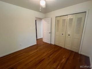 unfurnished bedroom featuring baseboards, wood finished floors, ceiling fan, and a closet