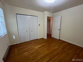 unfurnished bedroom with a closet, wood finished floors, and baseboards