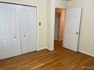 unfurnished bedroom with baseboards, a closet, and dark wood-style floors