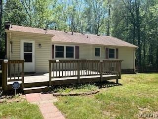 back of property featuring a deck and a lawn