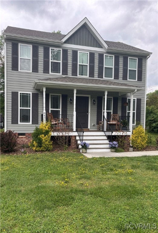 colonial inspired home with a porch, board and batten siding, and a front yard