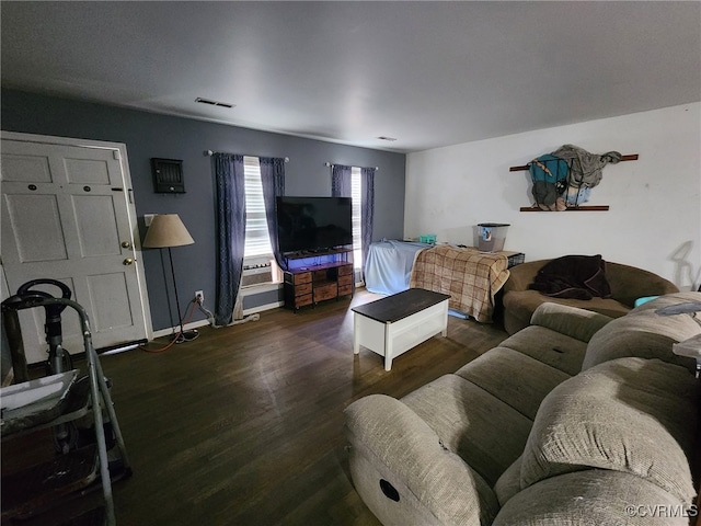 living room with baseboards, visible vents, and wood finished floors