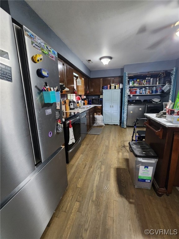kitchen featuring freestanding refrigerator, dark brown cabinetry, light wood-style floors, light countertops, and electric stove