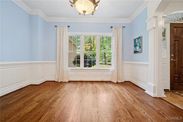 interior space with wood finished floors, decorative columns, a wainscoted wall, and visible vents