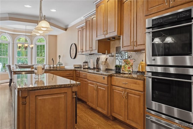 kitchen featuring crown molding, stainless steel double oven, black electric stovetop, light wood-type flooring, and a warming drawer