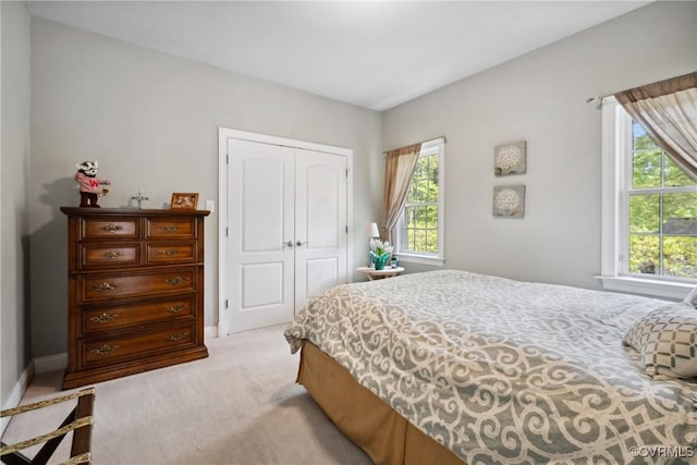bedroom with baseboards, light colored carpet, multiple windows, and a closet