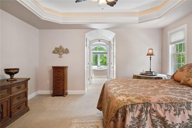 bedroom featuring light colored carpet, arched walkways, baseboards, ornamental molding, and a tray ceiling