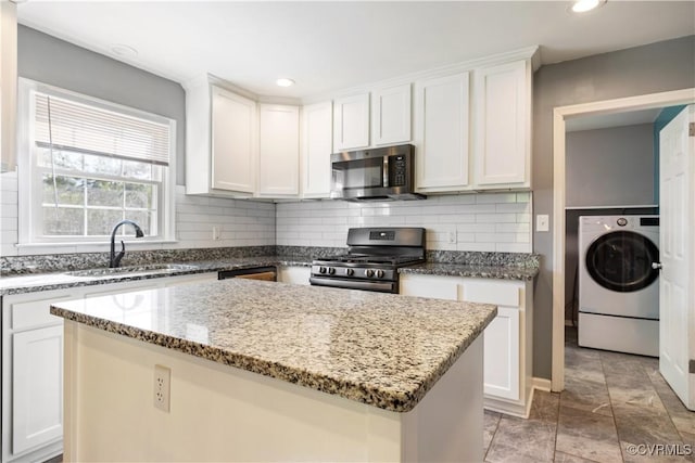 204 Pine St, Jarratt, VA 23867 - kitchen with appliances with stainless steel finishes, a sink, a center island, washer / dryer, and decorative backsplash
