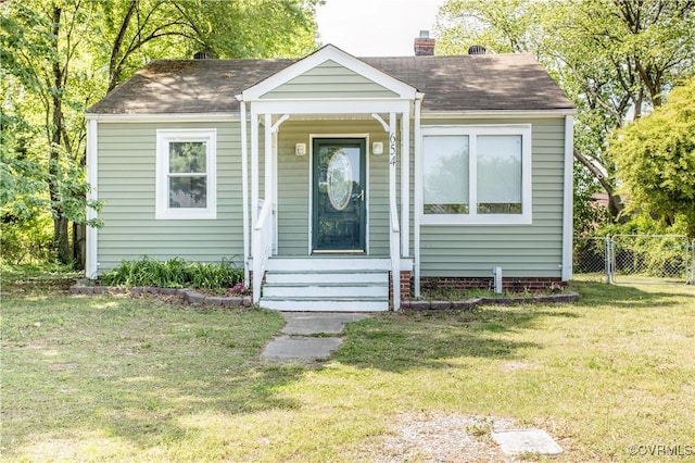 bungalow-style home with fence, a shingled roof, a chimney, and a front lawn