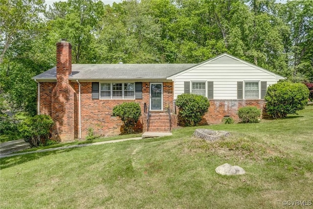 ranch-style home with brick siding, a chimney, a front yard, and roof with shingles