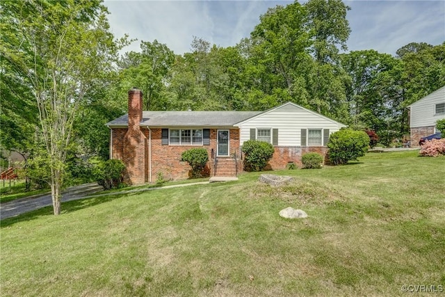 ranch-style house featuring brick siding, a chimney, and a front yard