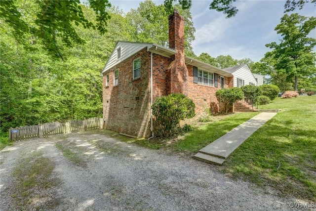 view of property exterior featuring a lawn, brick siding, fence, and a chimney