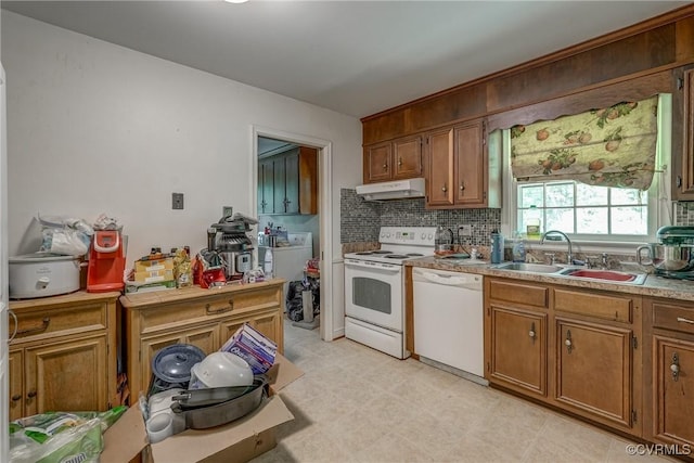 kitchen featuring brown cabinets, a sink, white appliances, tasteful backsplash, and under cabinet range hood