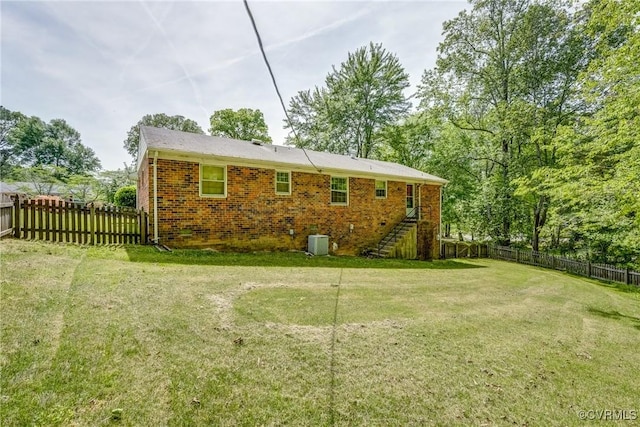 rear view of property with a yard, brick siding, stairs, and a fenced backyard