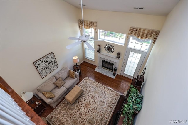 living room with visible vents, a ceiling fan, wood finished floors, and a premium fireplace