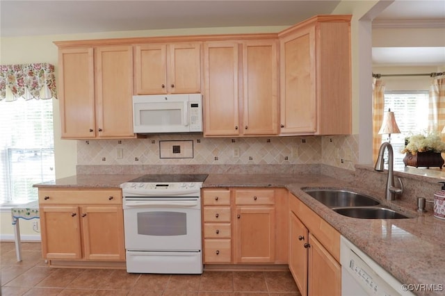 kitchen with a sink, light brown cabinetry, white appliances, and light stone counters