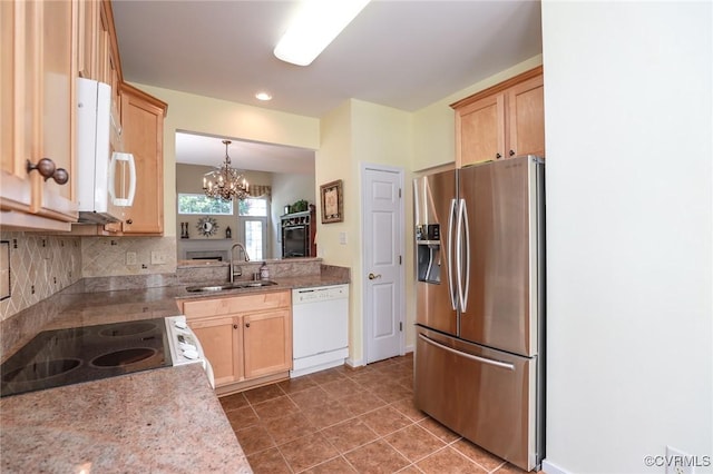 kitchen featuring light brown cabinets, white appliances, a chandelier, a sink, and backsplash