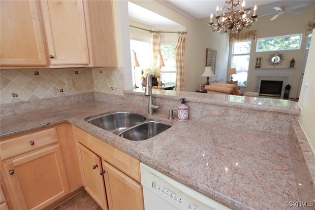 kitchen featuring backsplash, light brown cabinetry, a fireplace, a sink, and light stone counters