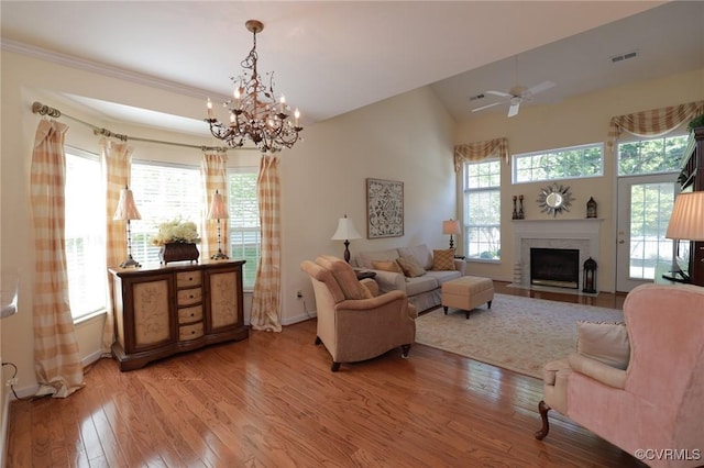 living room featuring a high end fireplace, baseboards, light wood finished floors, and visible vents