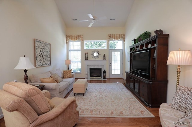 living area featuring visible vents, a high end fireplace, ceiling fan, and wood finished floors