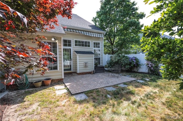 back of property featuring a yard, a patio, fence, and a shingled roof