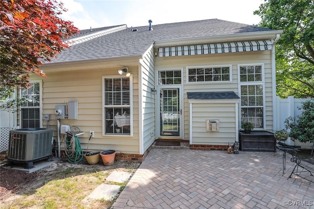 back of property with central AC unit, a patio area, roof with shingles, and fence