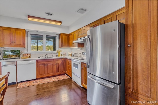 555 Rio Vis, Irvington, VA 22576 - kitchen with brown cabinets, under cabinet range hood, white appliances, dark wood-type flooring, and light countertops