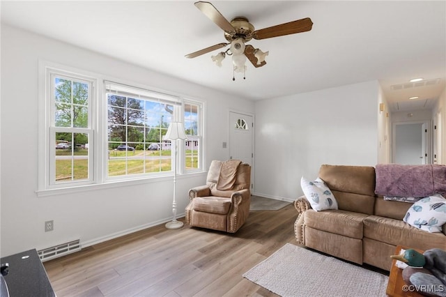living room featuring light wood-type flooring, visible vents, a ceiling fan, and a wealth of natural light