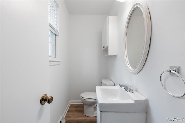 bathroom featuring wood finished floors, toilet, vanity, baseboards, and visible vents