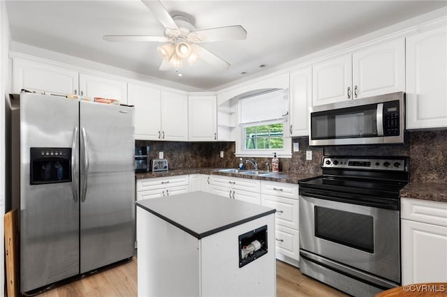 kitchen with dark countertops, stainless steel appliances, white cabinetry, and a sink
