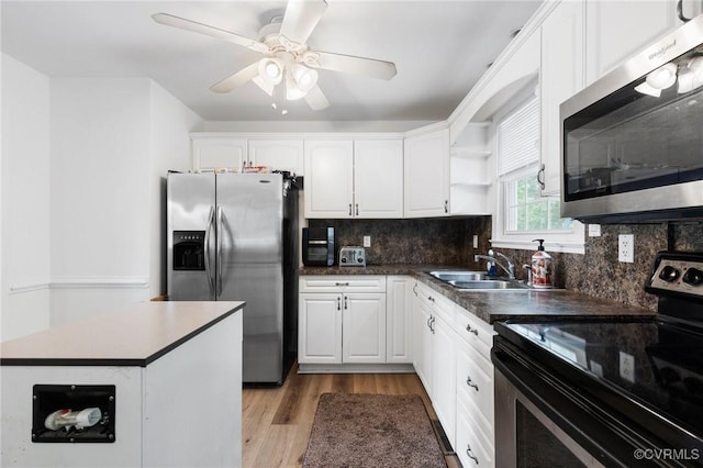 kitchen featuring tasteful backsplash, open shelves, white cabinets, a sink, and appliances with stainless steel finishes
