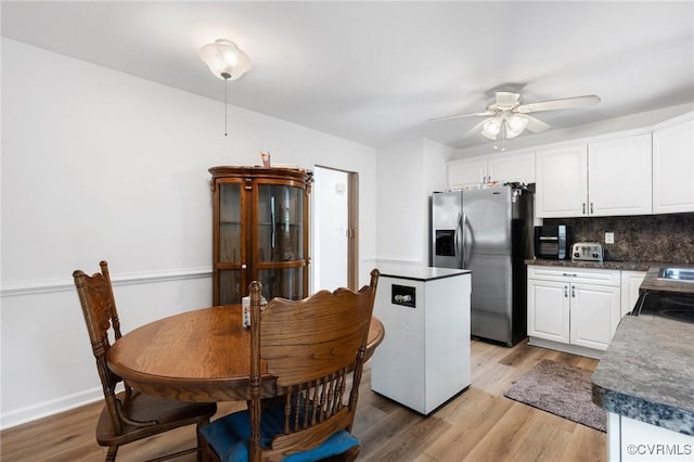 kitchen with light wood-style flooring, decorative backsplash, white cabinets, stainless steel refrigerator with ice dispenser, and a ceiling fan
