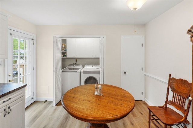 clothes washing area with independent washer and dryer, light wood-type flooring, cabinet space, and baseboards